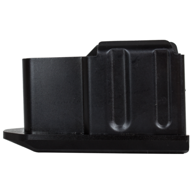The object, viewed from its side, resembles a black metallic box with ridged sides and a rectangular shape. It appears similar to the MAG CZ 557 .243/.308/6.5 CREEDMOOR 4 RD magazine, featuring a broad base and a small indentation on the left side.