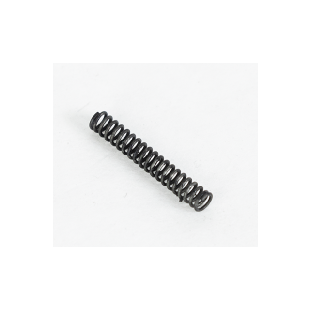 A compact, coiled metal spring named SLIDE STOP SPRING BREN 2 rests diagonally on a plain white surface, with one end slightly elevated. It exhibits a black appearance, tightly wound with a subtle shadow cast beneath it.