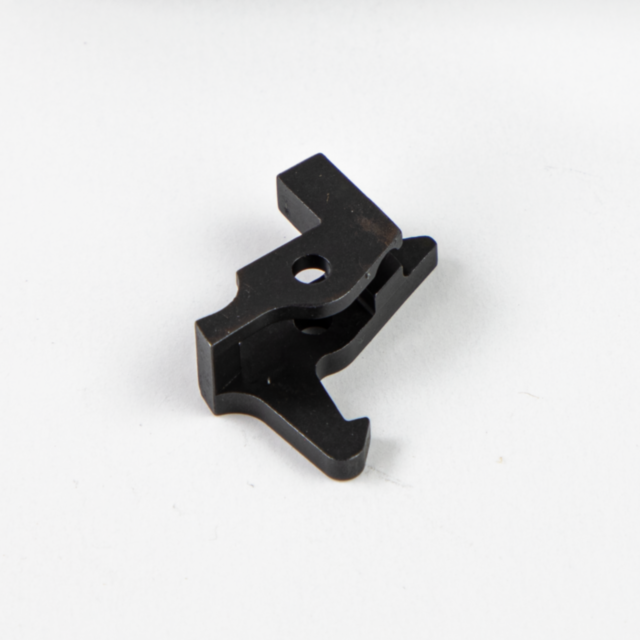 The SEAR BREN 2 is a small, black, metal bracket featuring a central hole and protruding edges, resting on a plain white surface.