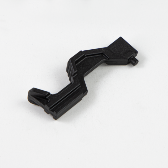 A black, L-shaped SLIDE STOP LEVER BREN 2 made of plastic with ridges and angles, resting on a plain white background. The lever has a small protrusion at one end.