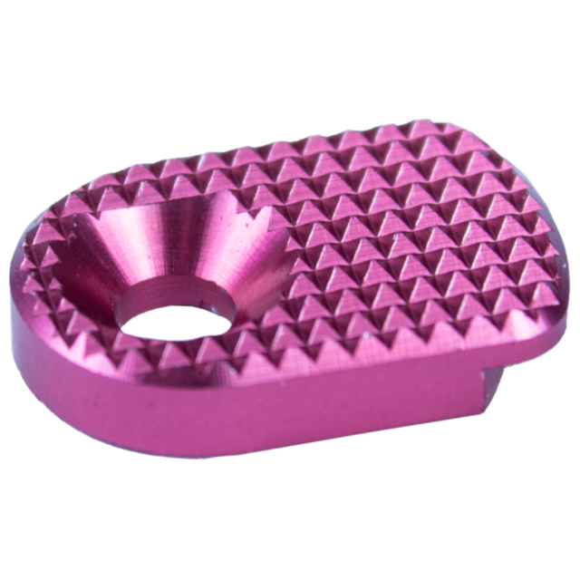 A close-up of the MAGAZINE CATCH PADDLE SHADOW 2 PINK, showcasing its compact, oval shape with a textured diamond-patterned metallic pink surface and a circular hole in the center.