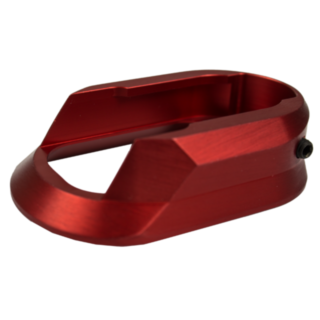 A stylish red metallic component, featuring smooth edges and an open rectangular design, likely the ALUMINUM MAGWELL SHADOW 2 RED for a mechanical or electronic device, casts a delicate shadow on the white background.