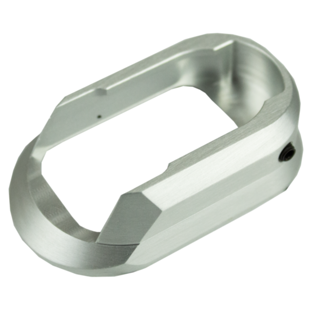 A rectangular bracket made from aluminum with a metallic silver color, featuring bevelled edges and a hollow center. This product, known as the ALUMINUM MAGWELL SHADOW 2 SILVER, has a smooth finish and includes a small circular hole on one side, likely fo