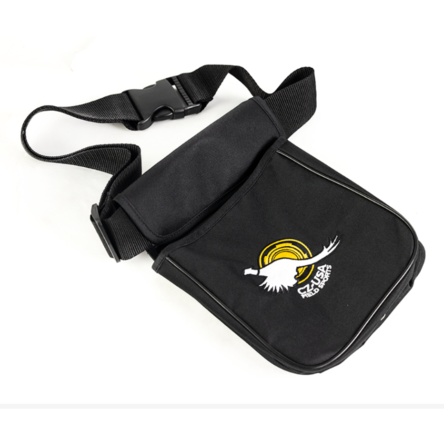 The CZUSA FIELD SPORTS SHELL POUCH is a black crossbody bag with an adjustable strap. It features a front flap adorned with an embroidered logo depicting a white bird with outstretched wings and a yellow circular design above, accompanied by text in anoth